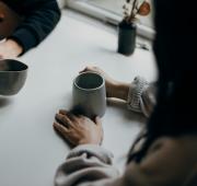 Twee mensen aan tafel met kopjes in hun hand