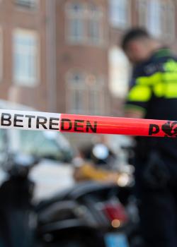 Situatie op straat met politiemedewerkers en een rood-wit lint met 'Niet betreden'