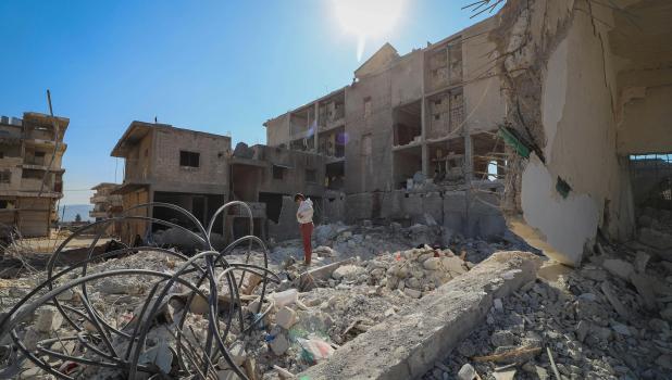 Persoon in resten van verwoest huis na aardbeving.